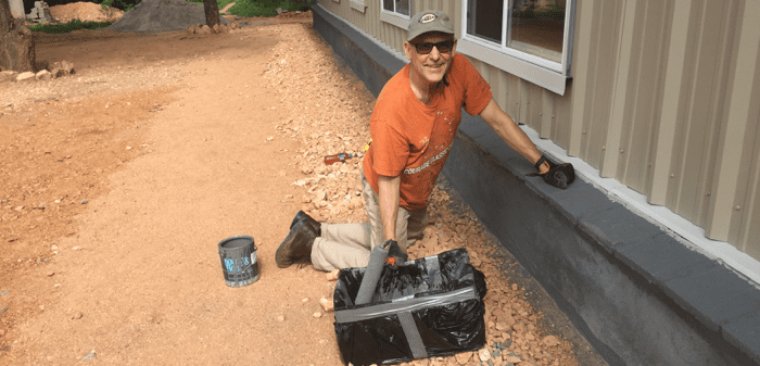 Applying sealer paint to base of the building.